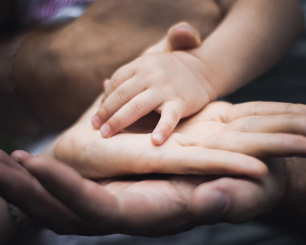 Manos de una familia unidas sobre la mano de un bebé