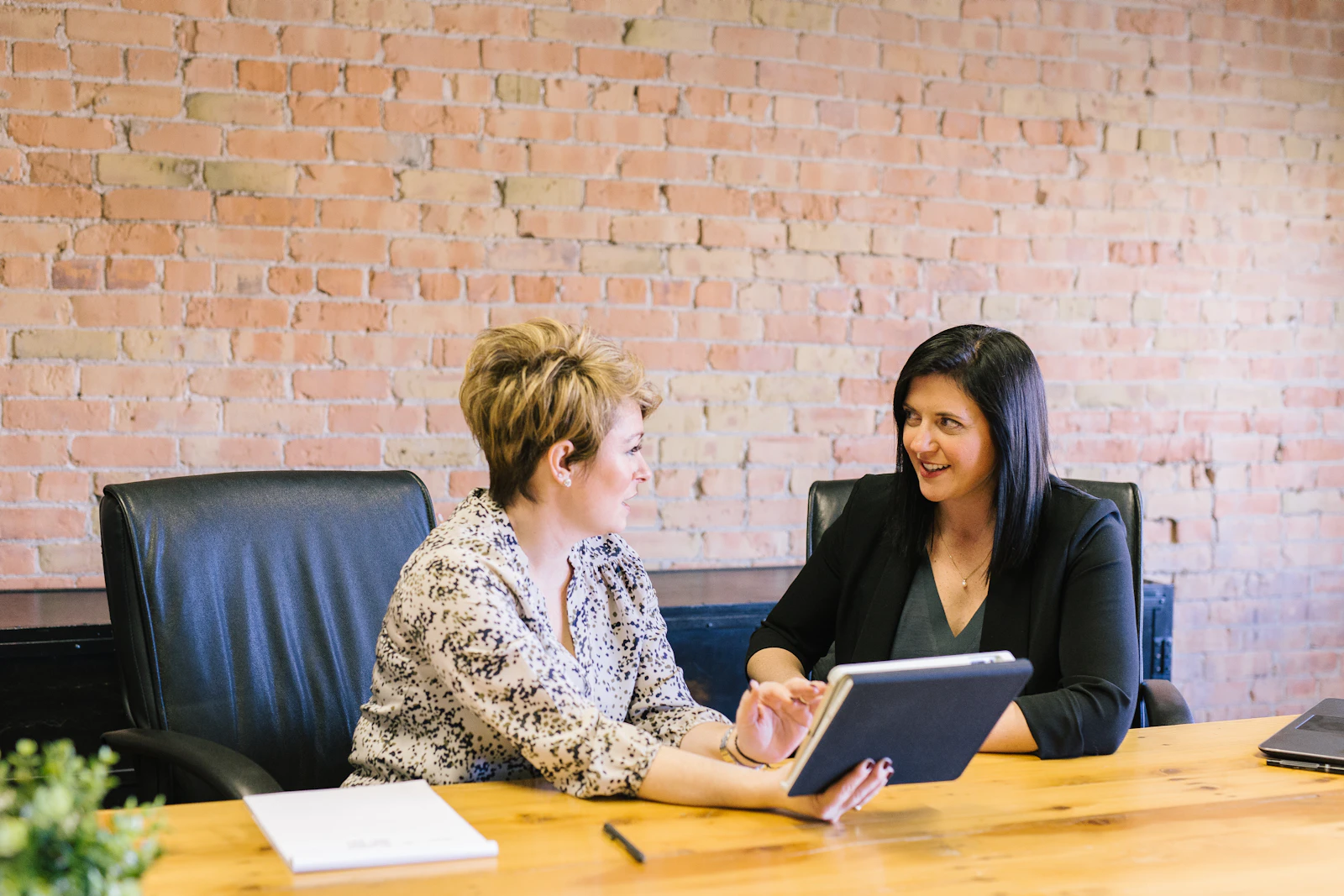 Dos mujeres conversan en una mesa de despacho durante una consulta