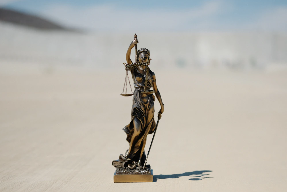 Figura de la justicia con balanza sobre una mesa