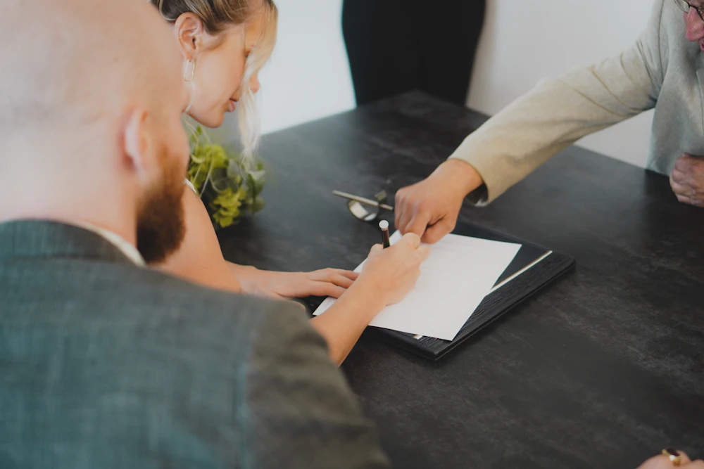 Dos personas firman un documento en un escritorio